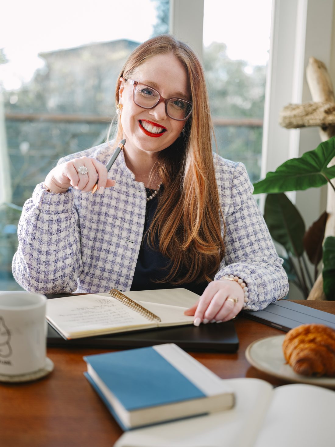 Dr. Monica Rysavy smiling at a desk by a window, notebook open