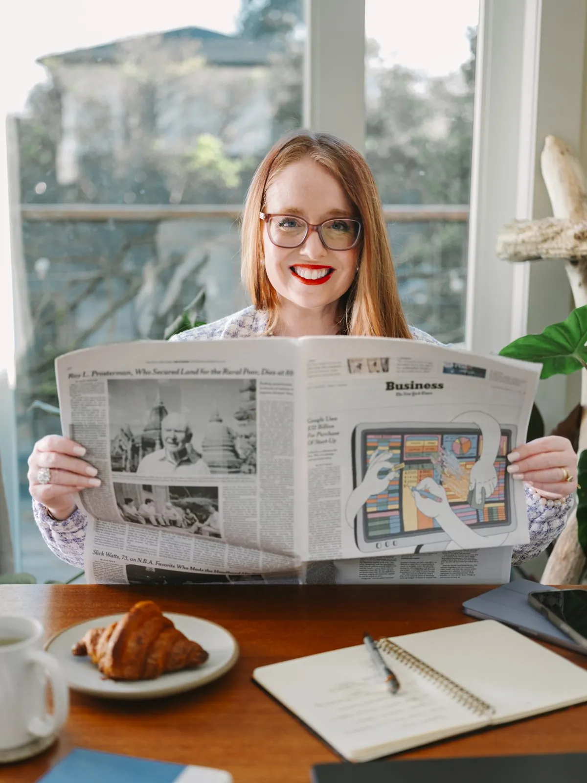 Dr. Monica Rysavy smiling over a newspaper at a sunny table